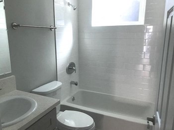 Millennium Apartments bathroom with sink, shower, and toilet Millennium Apartments bathroom with sink, shower, and toilet